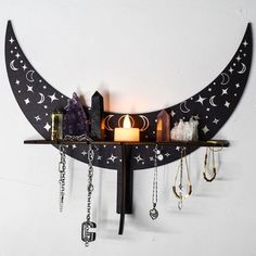 a wall mounted shelf with various items hanging from it's sides and a candle on top