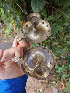 a person is holding two metal dishes in their hand and the other one has an odd shaped object on it