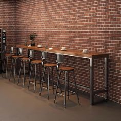 a brick wall with barstools and stools in front of it, next to a coffee machine