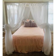 a bed with sheer curtains and pillows on it