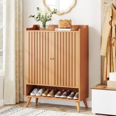 a wooden cabinet with shoes on it next to a mirror and coat rack in a room