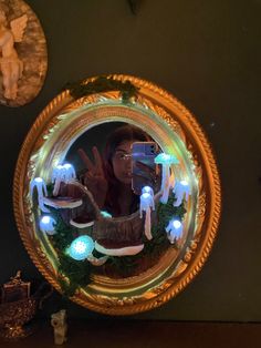 the reflection of a woman in a mirror with christmas decorations on it and lights around her