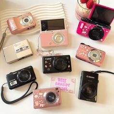 many different cameras sitting on top of a table next to a bowl of strawberries