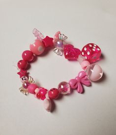 a close up of a bracelet on a white surface with pink beads and other items