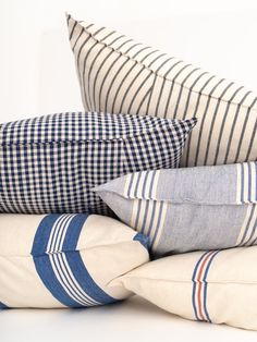 four pillows stacked on top of each other with blue and white striped pillowcases