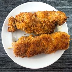 two pieces of fried chicken on a white plate with toothpicks in it,