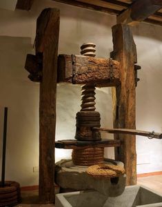 an old fashioned water pump in a museum setting with wood beams and stone blocks on the floor