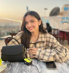 a woman sitting at a table with a purse and cell phone