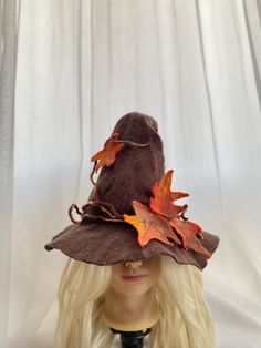 a blonde wig wearing a brown hat with leaves on the brim and side part