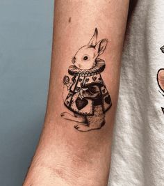 a tattoo on the arm of a man with a rabbit in a dress and bow tie