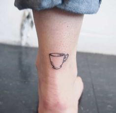 a small coffee cup tattoo on the ankle is shown in black ink, and it appears to be half - finished