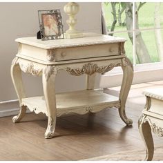 a white table with an ornate design on it and a bench in front of the window