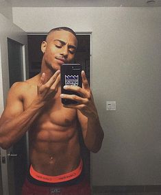 a shirtless man taking a selfie in front of a mirror with his cell phone