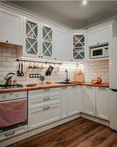 a kitchen with white cabinets and wooden floors