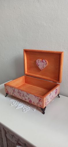 a wooden box with a heart shaped decoration on the lid sitting on a white table