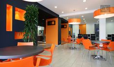 an office with orange chairs and black tables