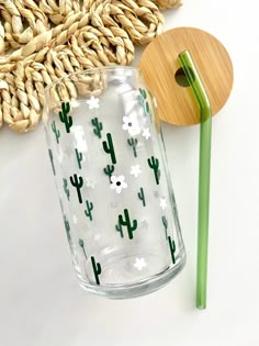 a glass vase sitting next to a straw hat and a wooden spoon on a white surface