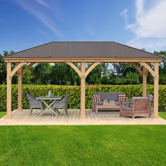 a wooden gazebo sitting on top of a lush green field next to a picnic table