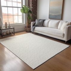 a living room with a white couch and wooden flooring next to a large window