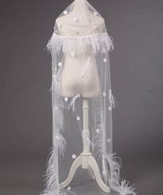 a mannequin wearing a veil with white feathers on it