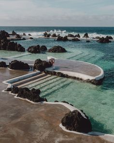 the water is crystal clear and blue with waves coming in from the rocks on the shore