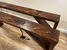 a wooden bench sitting on top of a hard wood floor next to a white wall