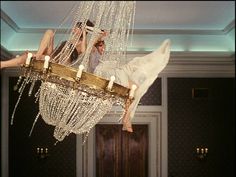 two people hanging from a chandelier in a room