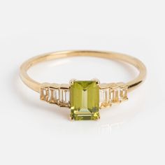 a yellow gold ring with an emerald and baguette cut diamonds on the side