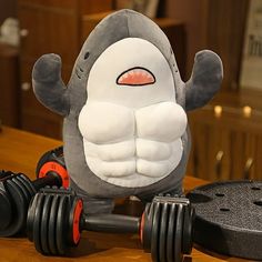 a stuffed animal sitting on top of a wooden table next to two dumbbells