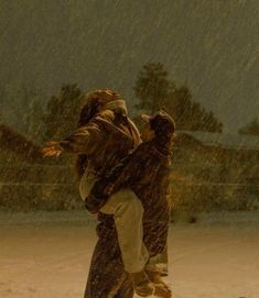 two people are playing in the snow with an umbrella