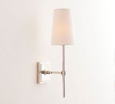 a white lamp mounted on the wall next to a light fixture with a fabric shade