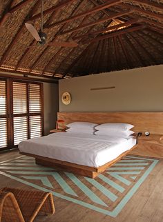 a bed sitting inside of a bedroom on top of a wooden floor next to windows