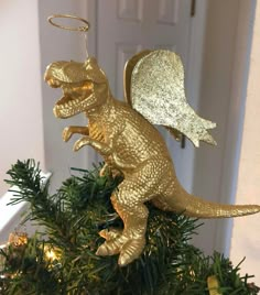 a gold dinosaur ornament hanging from a christmas tree