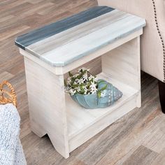 a blue vase with white flowers sitting on a wooden shelf next to a chair and ottoman