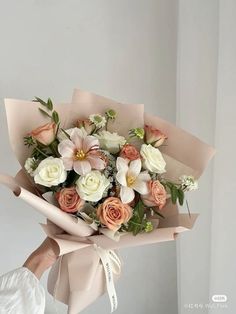 a woman holding a bouquet of white and pink flowers in her left hand, with the rest of her arm wrapped around it