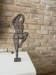 a sculpture is sitting on top of a white pedestal in front of a brick wall