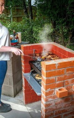 a woman standing in front of an outdoor bbq grill with food cooking on it