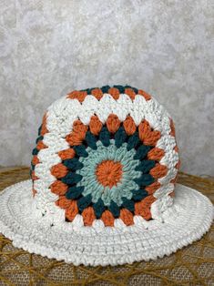 a white crocheted hat with an orange and blue center