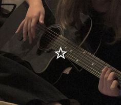 a woman is playing an acoustic guitar with the star sticker on her left hand