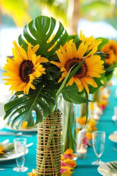 a vase filled with yellow sunflowers sitting on top of a blue table cloth