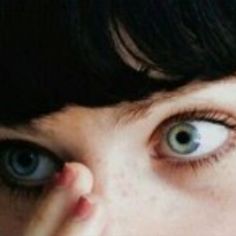 a close up of a person's eye with one hand on their face and the other