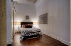 a bed room with a neatly made bed and hard wood flooring next to a doorway