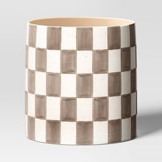 a white and brown checkered coffee mug on a gray background with the lid off