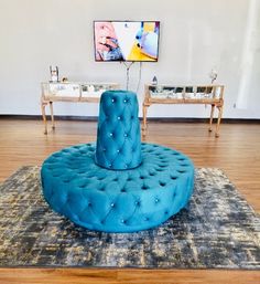 a blue round couch sitting on top of a rug in a living room next to a table