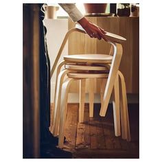 a person standing in front of a stack of chairs with their hand on the chair