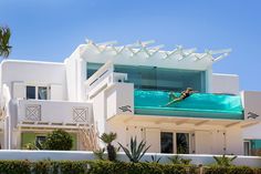 a person swimming in the pool on top of a large white building with balconies