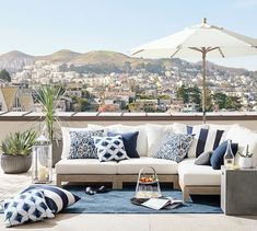 a living room filled with lots of furniture and an umbrella on top of a roof