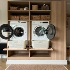 two washers and dryers are sitting in front of a shelf with baskets on it