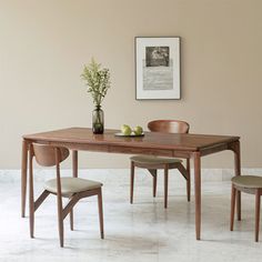 a wooden table with two chairs and a vase on top of it next to a bowl of fruit