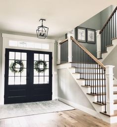 an entryway with stairs and wreaths on the door